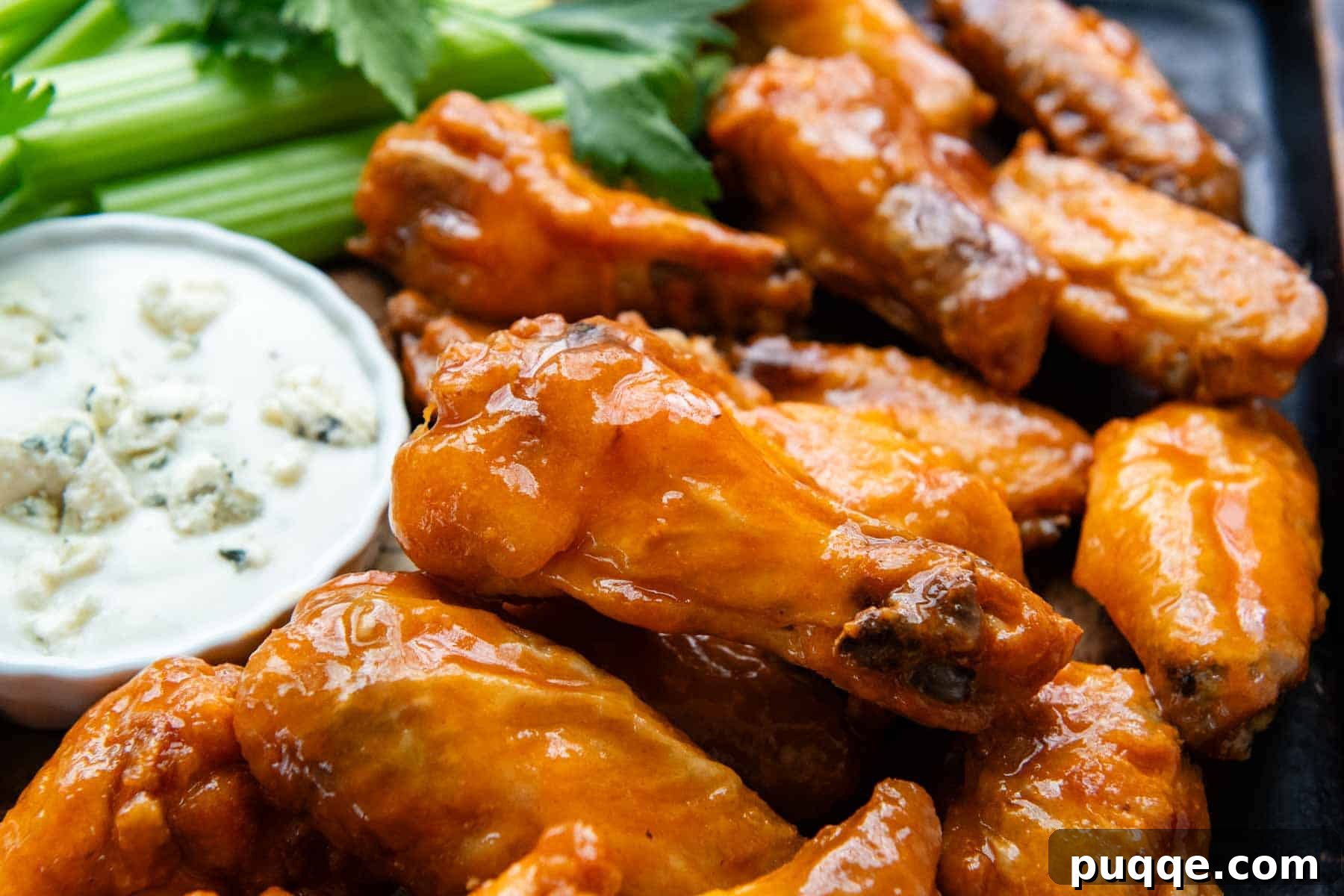 A vibrant platter of gluten-free buffalo wings, served with celery sticks and a bowl of blue cheese dressing, ready to be enjoyed.