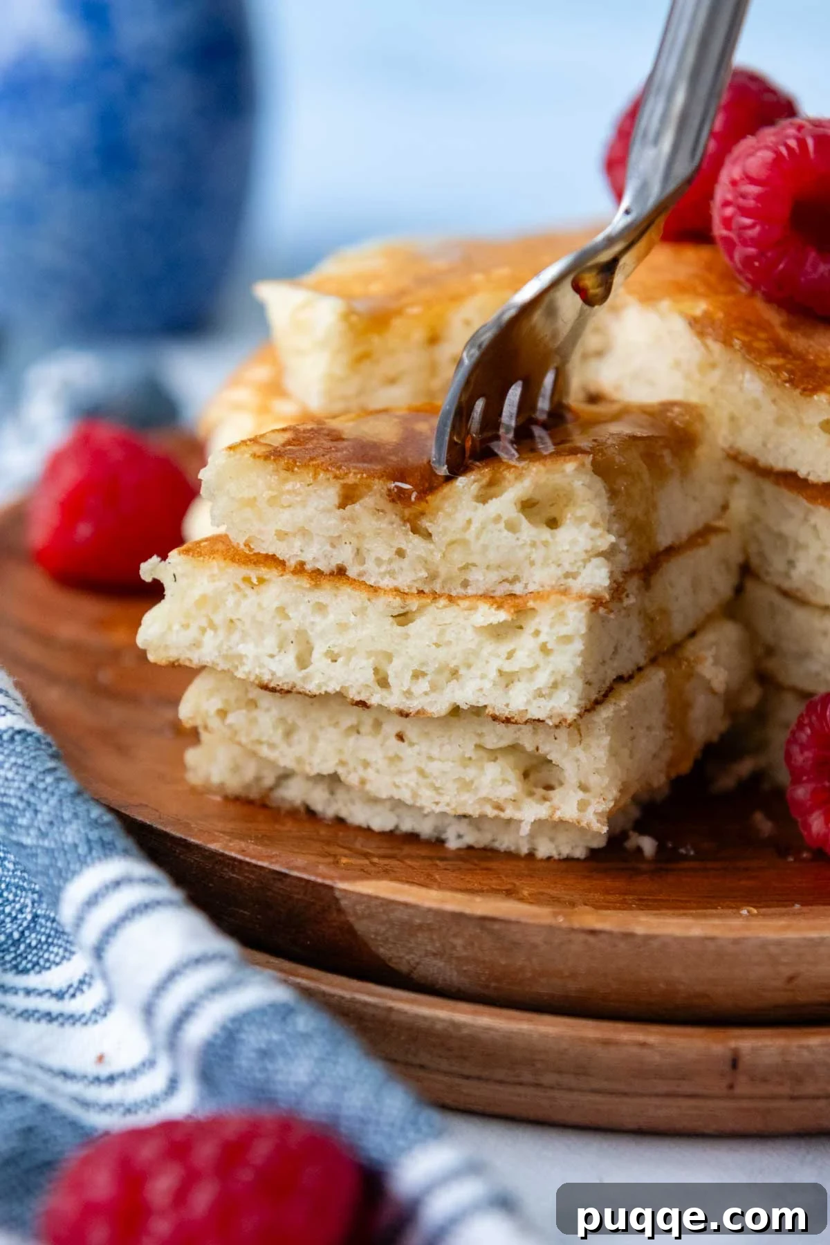 A fork piercing a stack of golden, fluffy gluten-free pancakes, showcasing their light and airy texture.