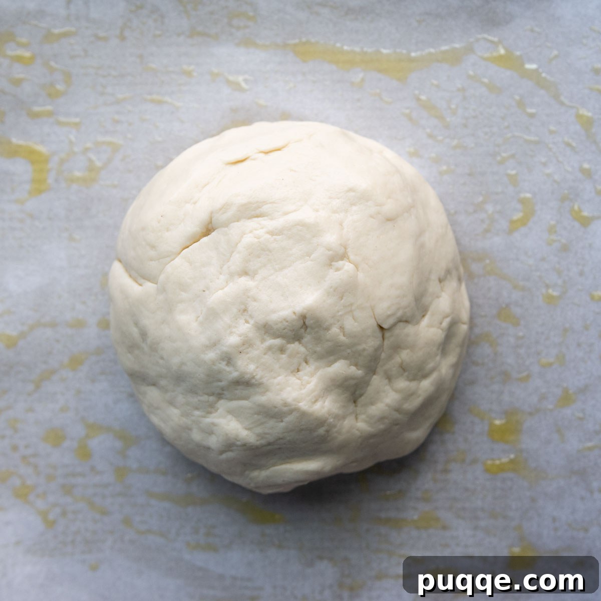 Pillowy Soft Gluten-Free Calzones 4 A smooth, round ball of gluten-free calzone dough, expertly formed on greased parchment paper.