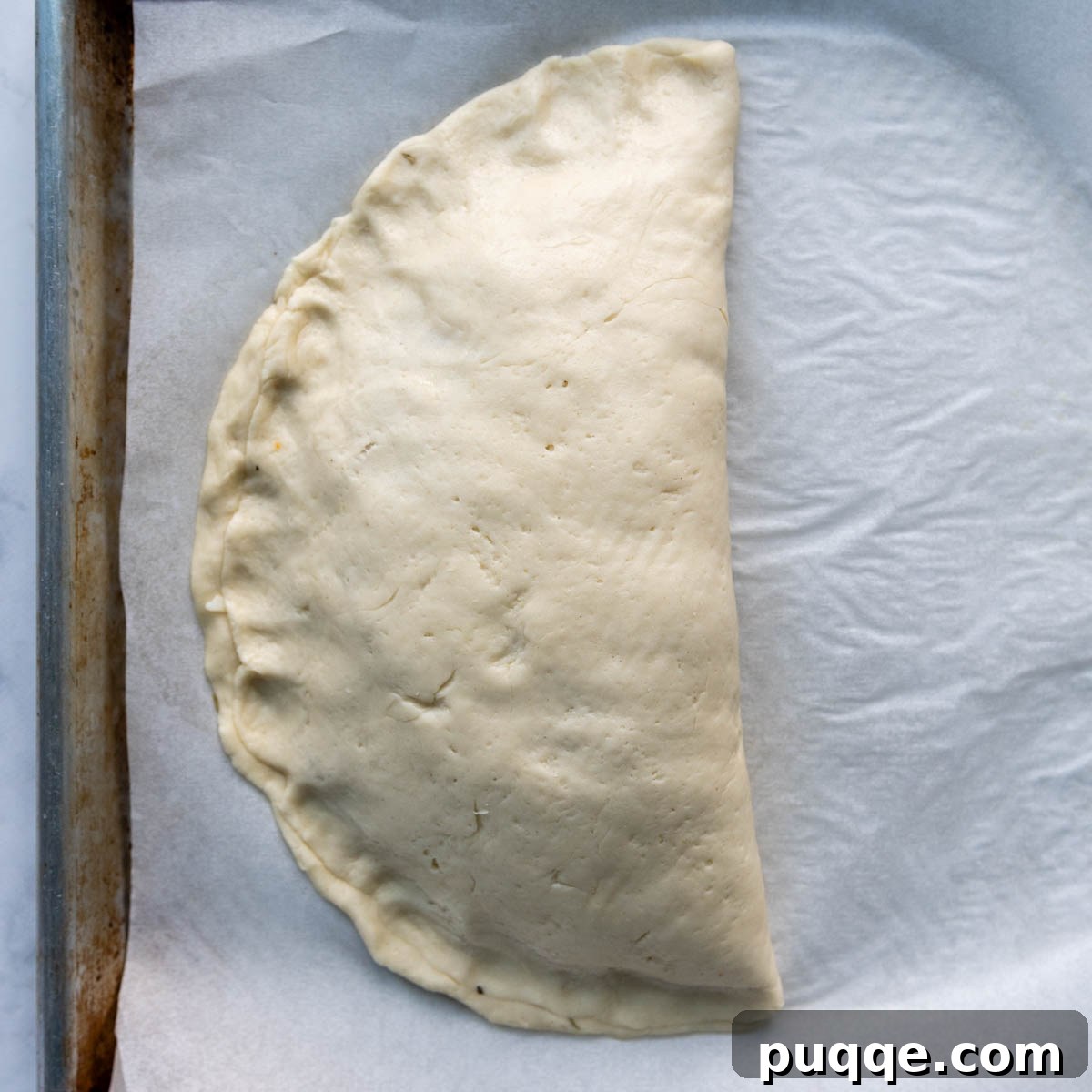 Pillowy Soft Gluten-Free Calzones 7 The folded calzone dough with edges being firmly pressed together to create a secure seal.