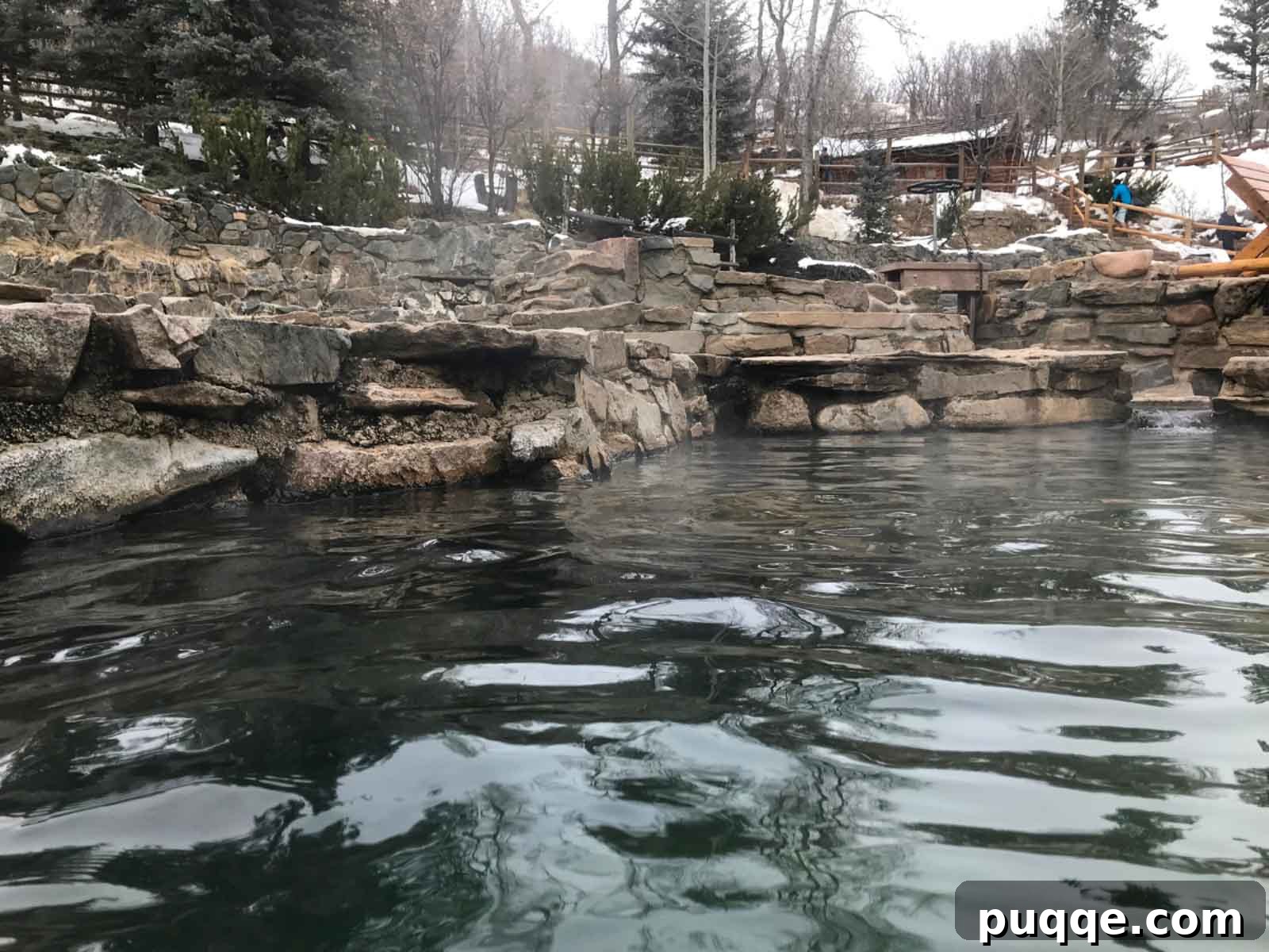 The serene and natural pools of Strawberry Park Hot Springs in a snowy forest setting