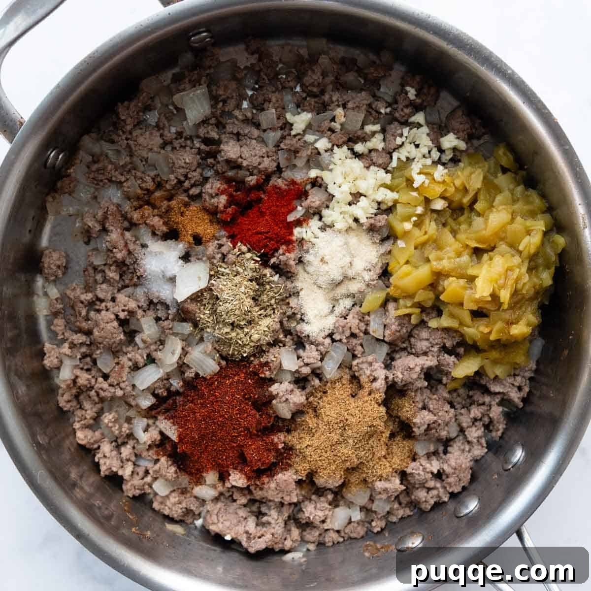 Ultimate Gluten-Free Cheesy Beef and Bean Enchiladas 3 Ground beef and diced onions cooking in a skillet with seasonings being added.