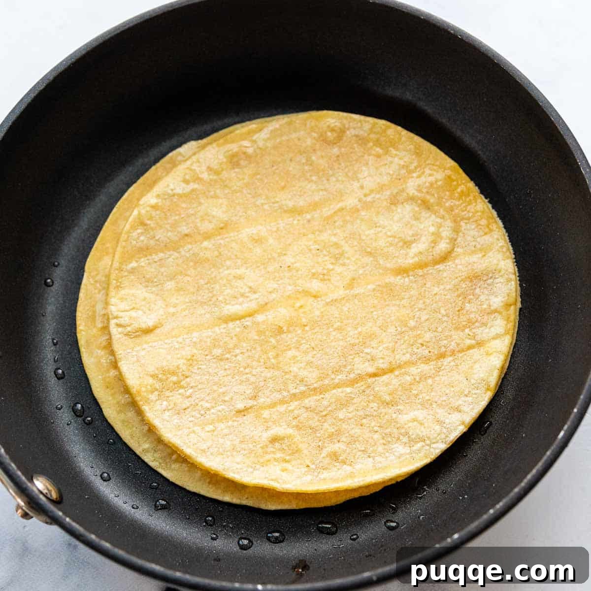 Ultimate Gluten-Free Cheesy Beef and Bean Enchiladas 5 Three corn tortillas being warmed simultaneously in a greased skillet.