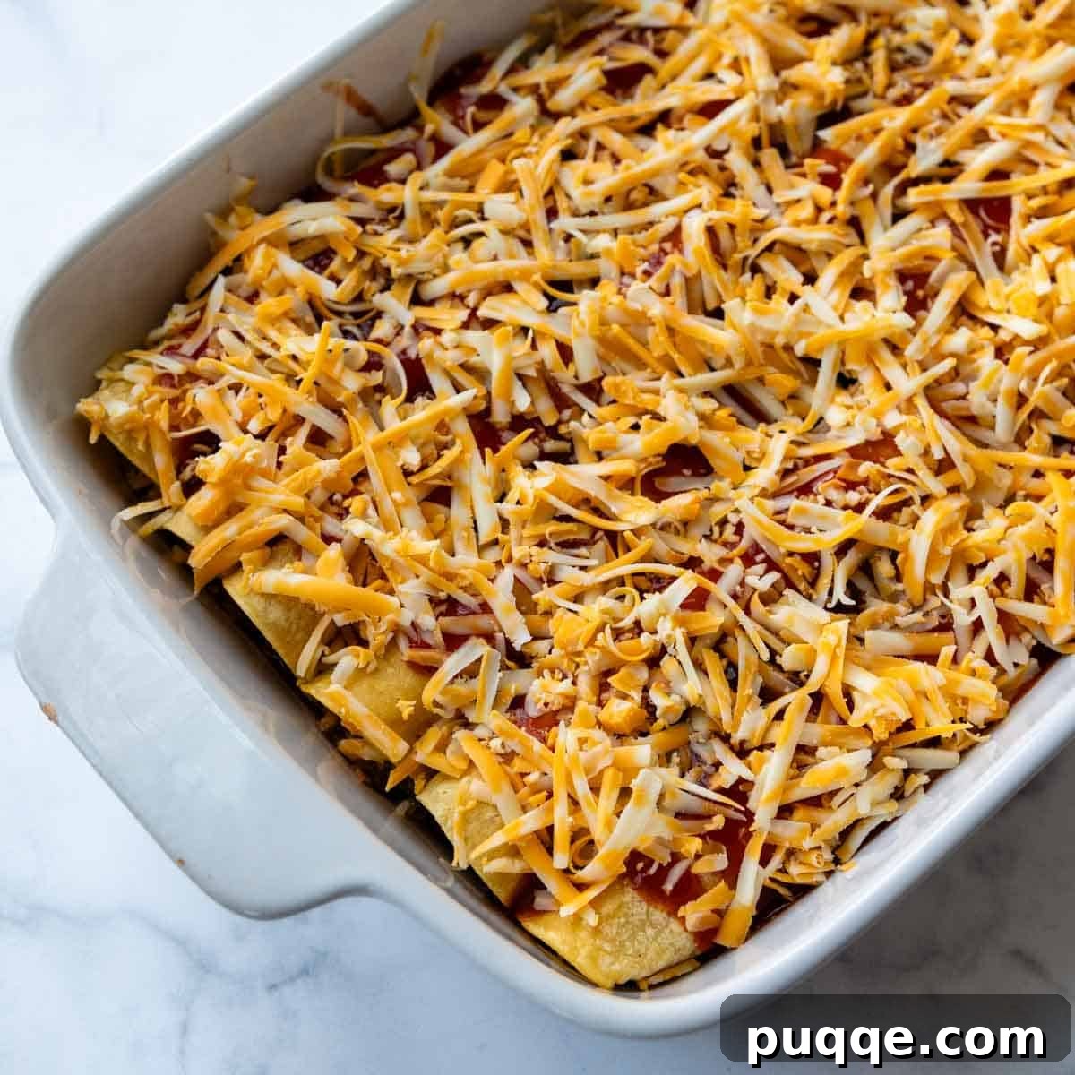 Ultimate Gluten-Free Cheesy Beef and Bean Enchiladas 8 The unbaked enchiladas in the casserole dish, covered with enchilada sauce and a final layer of cheese.