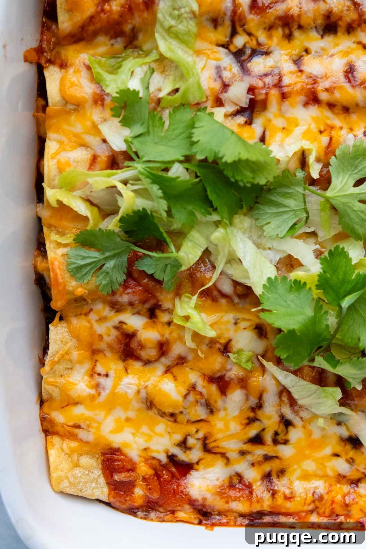 Ultimate Gluten-Free Cheesy Beef and Bean Enchiladas 10 An overhead shot of the baked enchilada casserole, generously topped with melted cheese and fresh garnishes.
