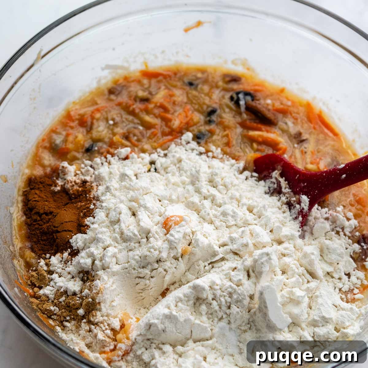 Dry gluten-free flour and spices being gently stirred into the wet mixture in a bowl.