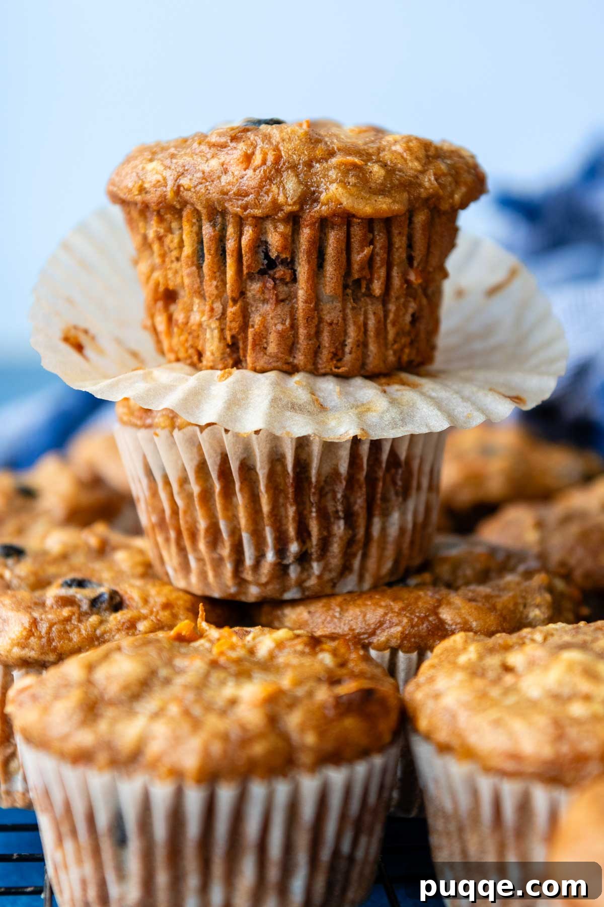 A stack of two perfectly baked gluten-free morning glory muffins with their paper liners removed, revealing a moist texture.