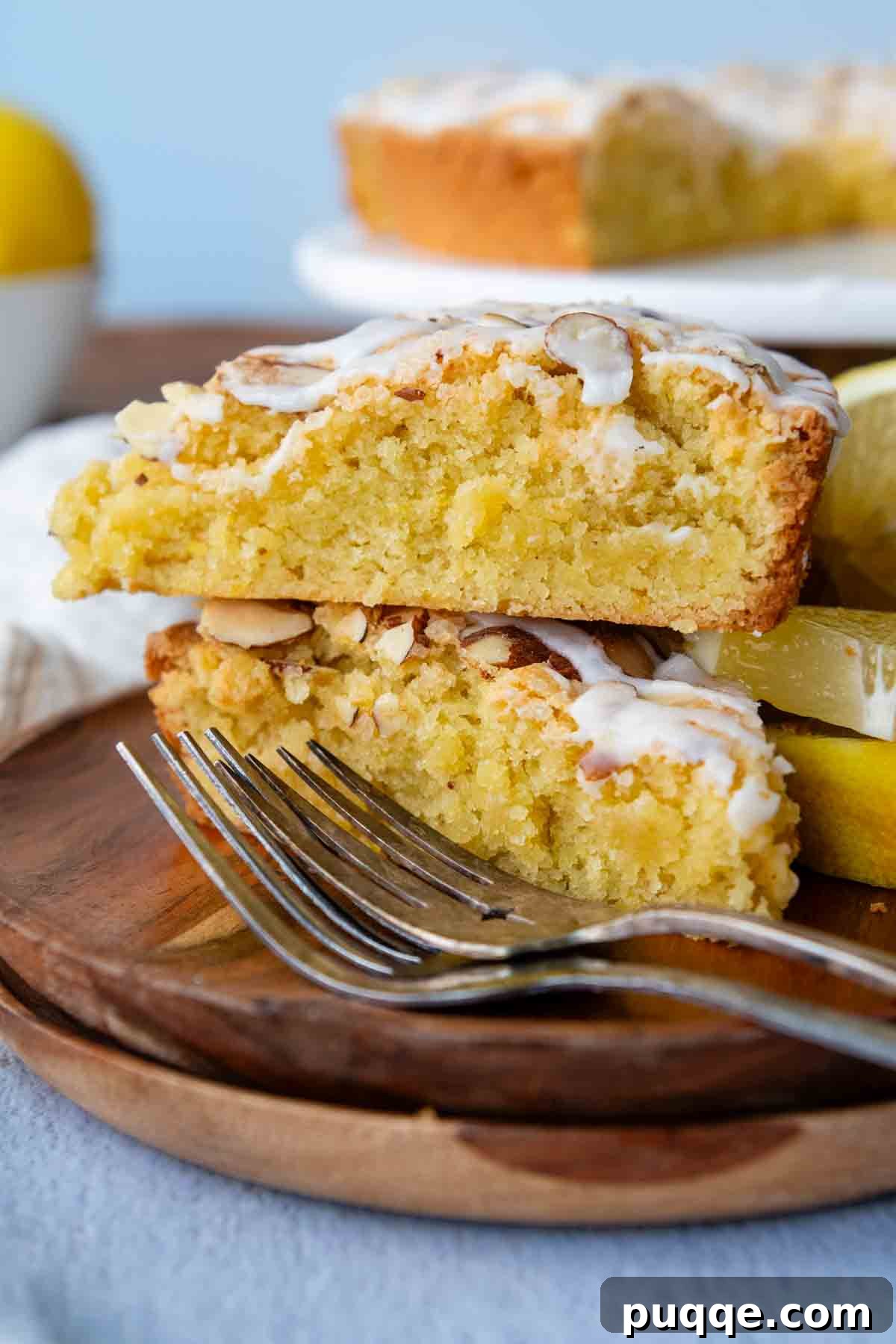A charming stack of two slices of moist almond flour lemon cake, showcasing its tender crumb and inviting texture.