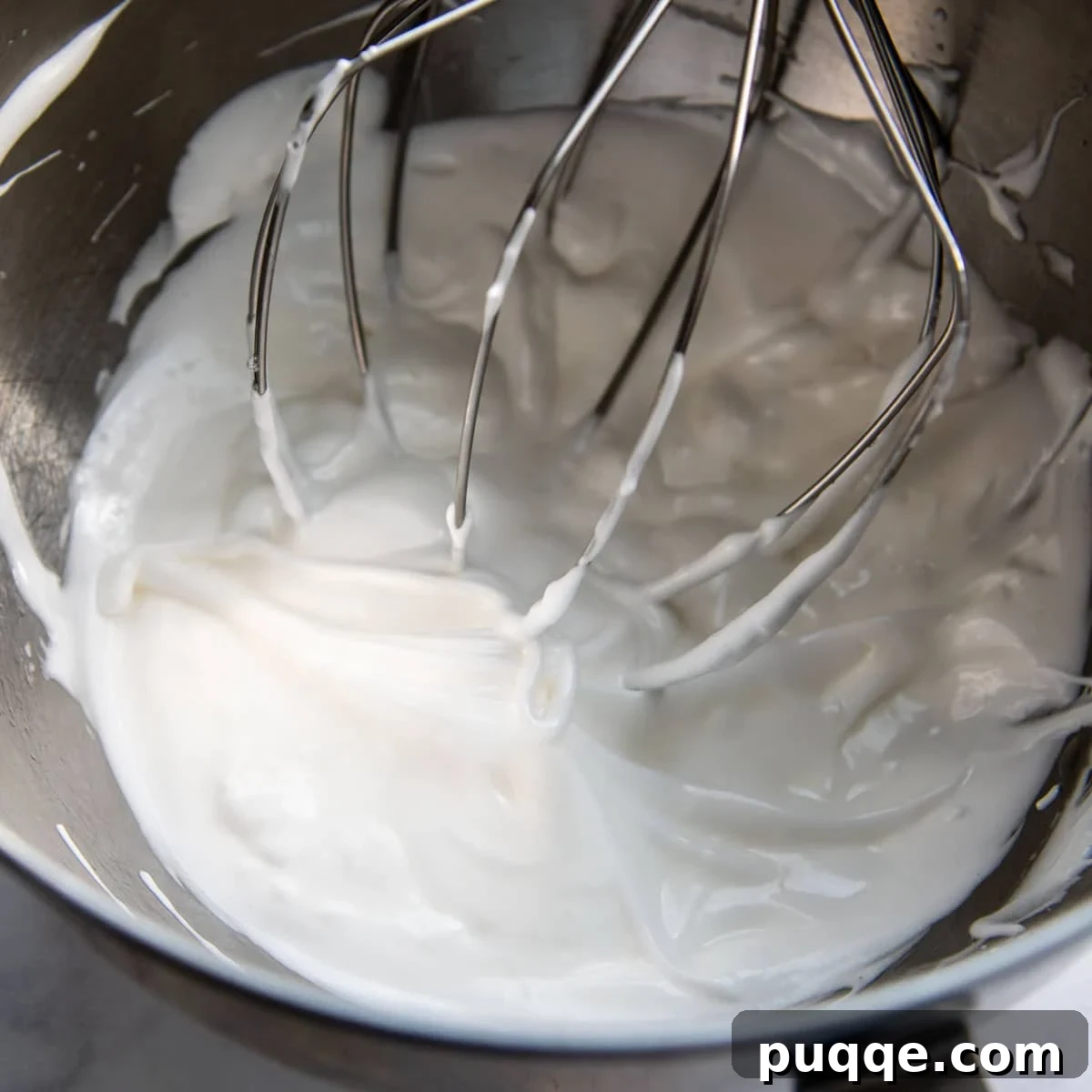 Perfectly beaten egg whites forming stiff, glossy peaks in a large mixing bowl, ready to be folded into the cake batter for ultimate fluffiness.