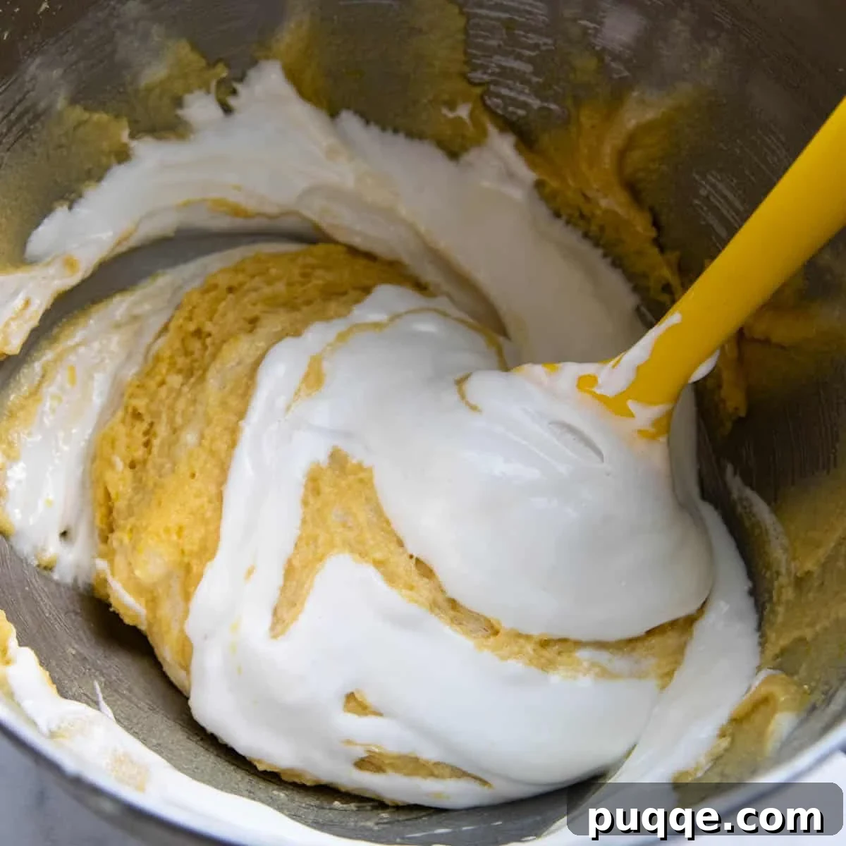 Gently folding in the beaten egg whites into the almond flour mixture, demonstrating the technique for maintaining air.