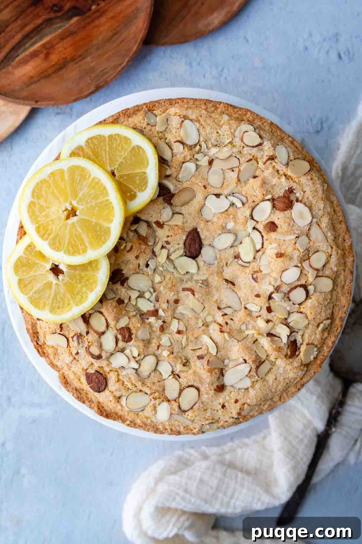 An overhead view of the baked almond flour lemon cake, artfully arranged with fresh lemon slices around its perimeter, showcasing the golden crust.