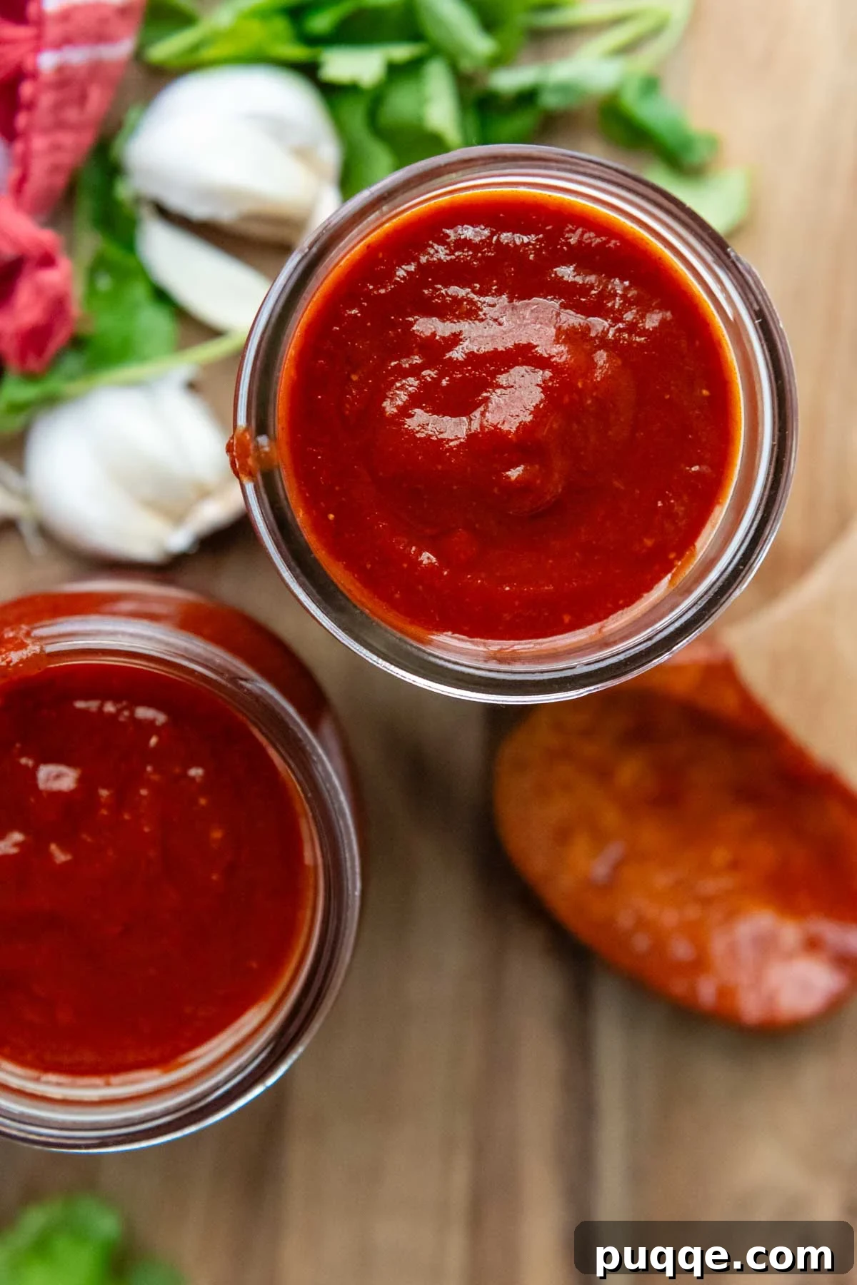 top view to 2 glass jars with sauce and a wooden spoon next to it.