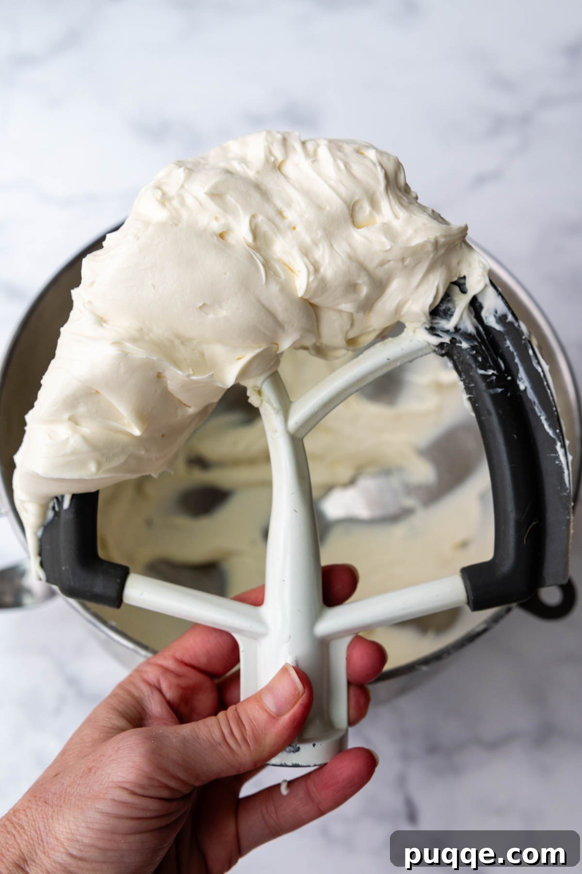 Cloud-Like Gluten-Free Banana Cake 8 A whisk attachment covered in light, fluffy whipped cream cheese frosting, demonstrating its perfect consistency.