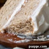 A slice of gluten free banana cake with a bite taken out, displaying its soft crumb and frosting.