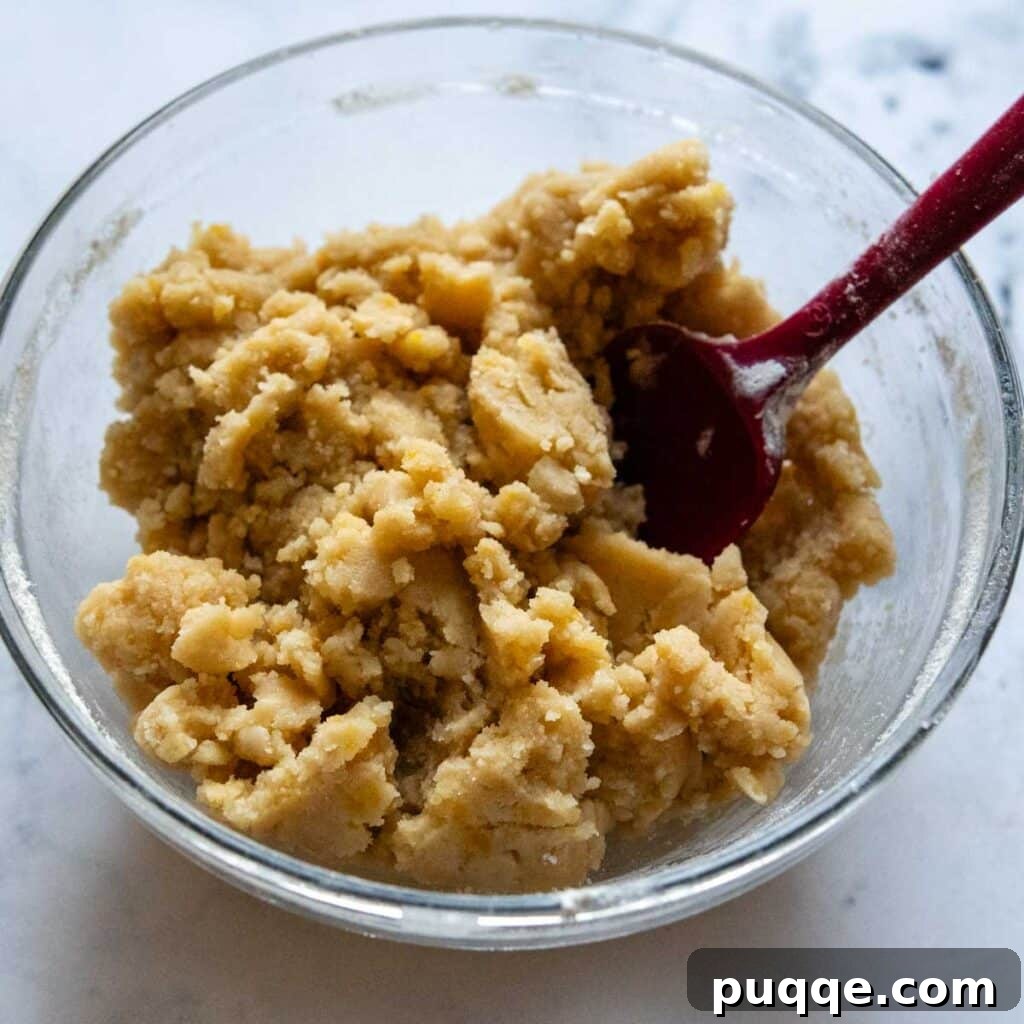 A close-up shot of the golden, crumbly gluten-free streusel topping mixture in a bowl, ready to be sprinkled over the pie.