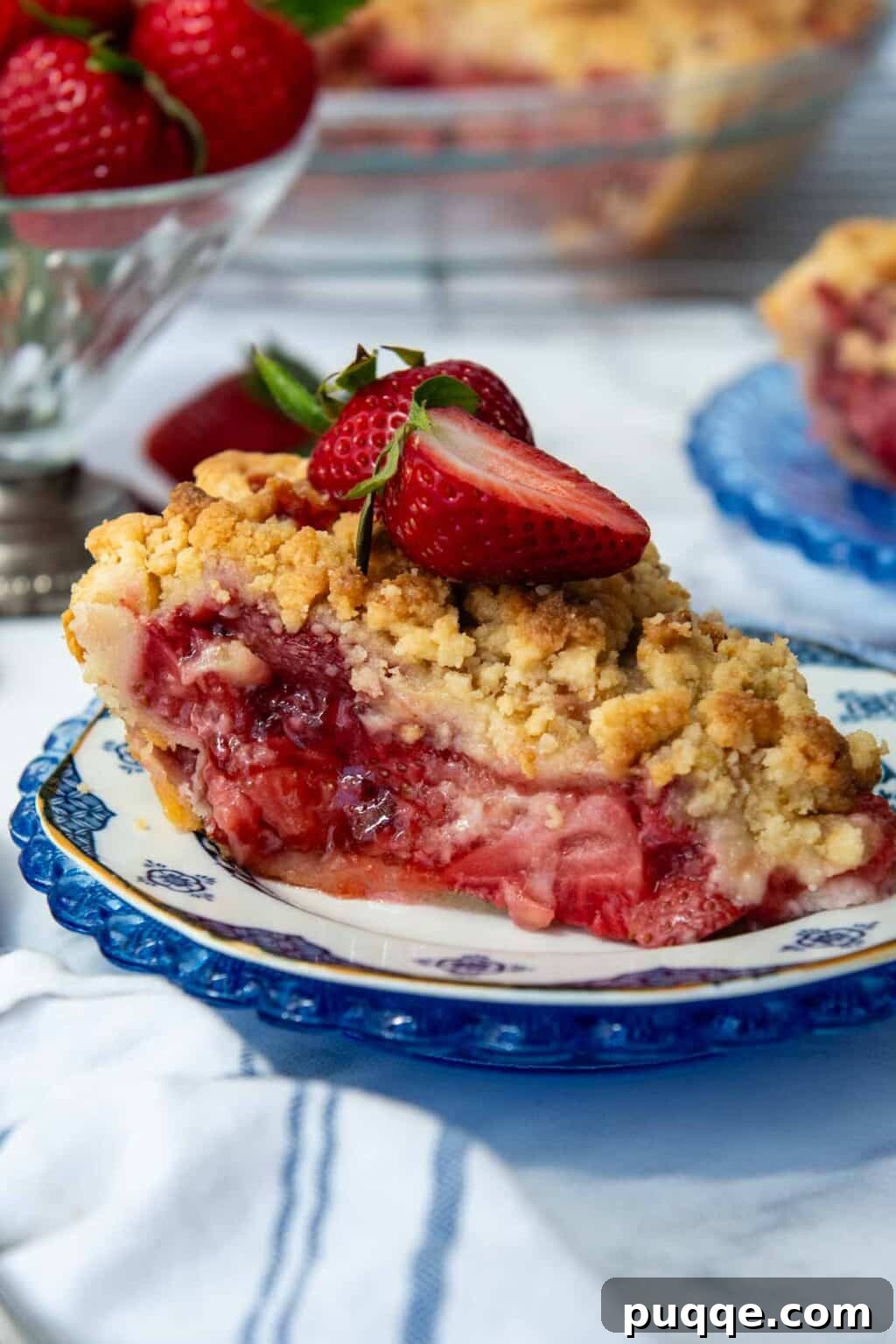 A delectable slice of gluten-free strawberry pie, adorned with fresh strawberries, showcasing its thick, perfectly set filling and golden streusel topping.