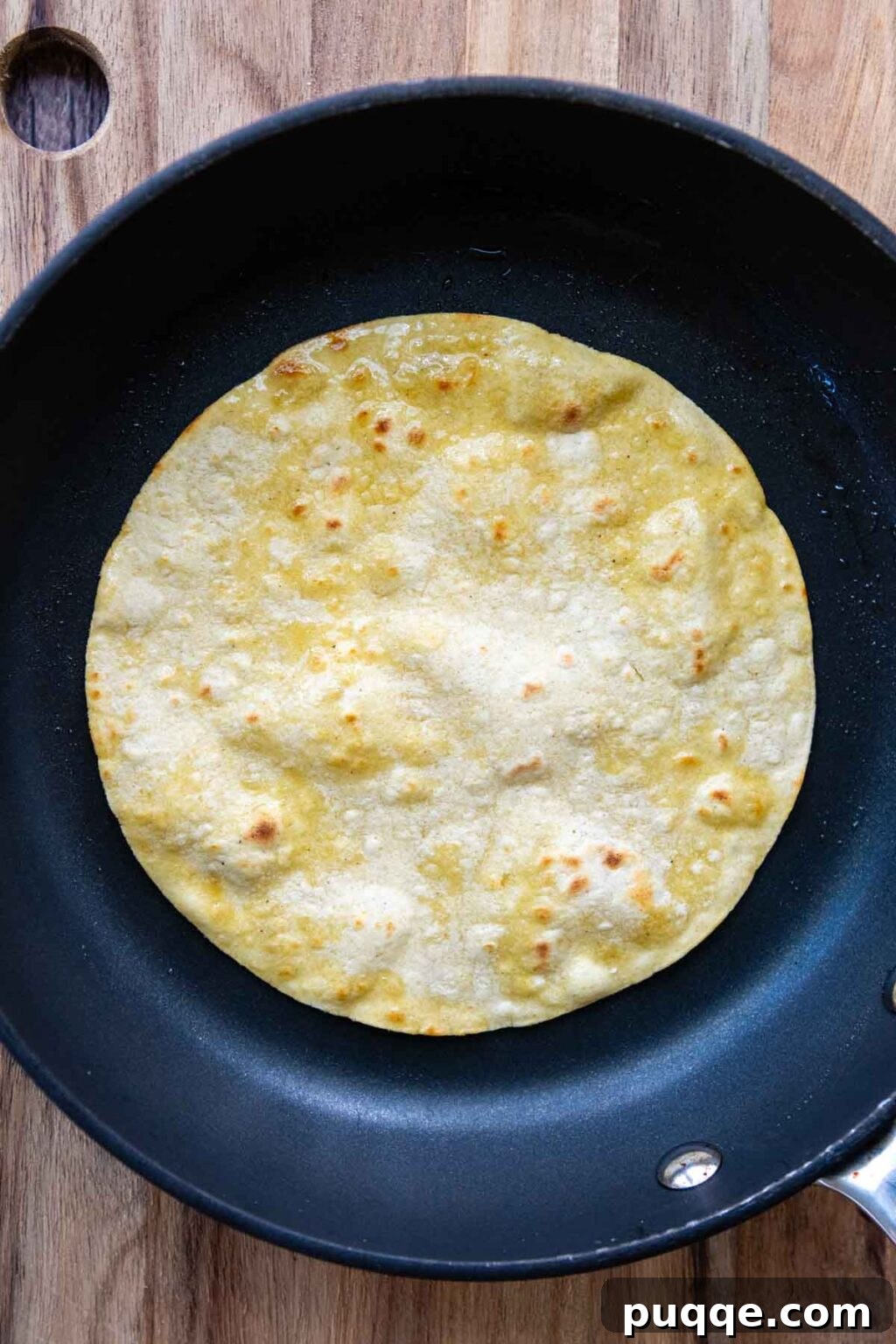 Revolutionary Gluten Free Weeknight Tacos 7 A golden-brown corn tortilla gently frying in a skillet, preparing it for a soft, pliable, and flavorful taco experience.
