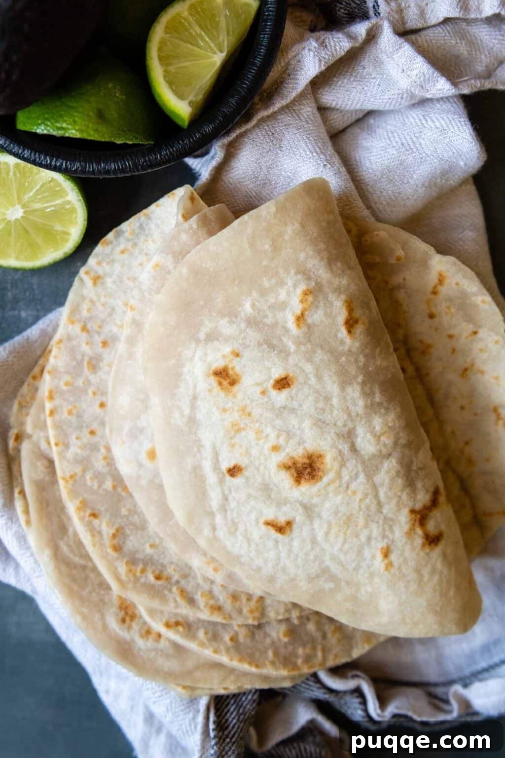Revolutionary Gluten Free Weeknight Tacos 8 A stack of soft, flexible homemade gluten-free flour tortillas, folded and ready for fillings, with a fresh lime wedge nearby.