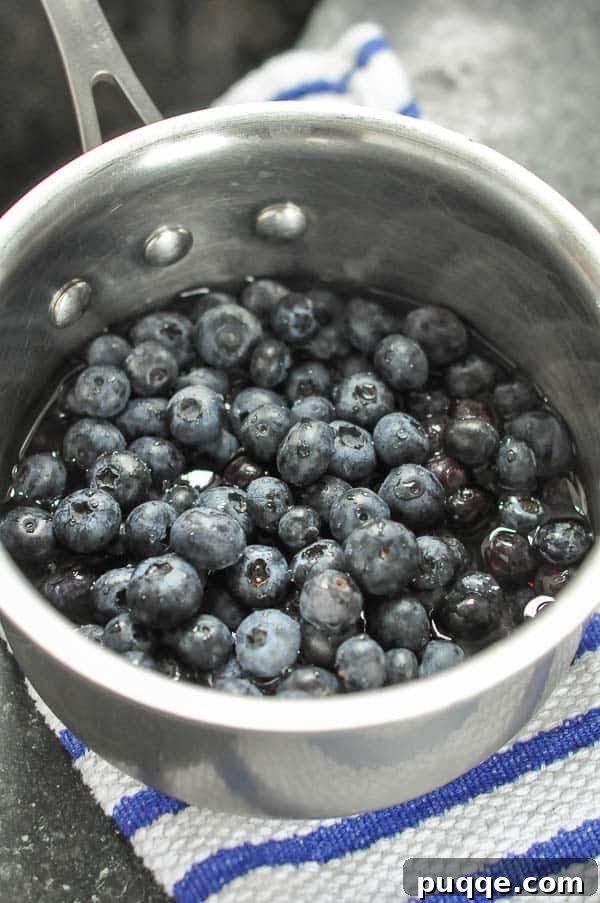 Homemade 10-Minute Maple Blueberry Syrup 3 A small pot of blueberries, water, and maple syrup gently simmering on the stovetop.