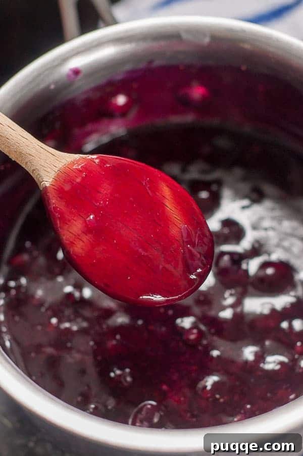 Homemade 10-Minute Maple Blueberry Syrup 5 The back of a wooden spoon showing how the blueberry syrup should coat it when thickened.