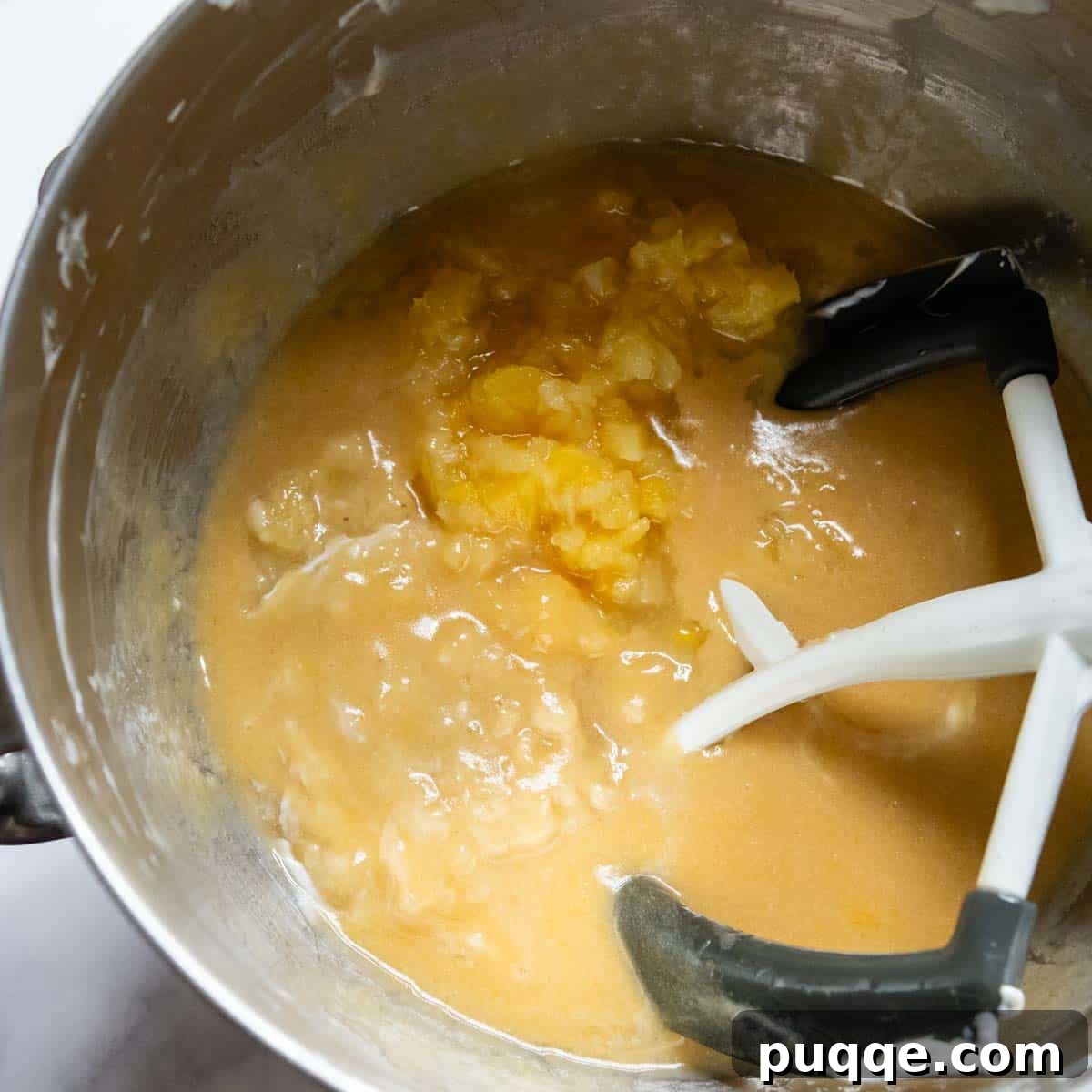Tropical & Tender Gluten-Free Hummingbird Cake 4 Crushed pineapple and mashed bananas being added to the cake batter in a mixing bowl.