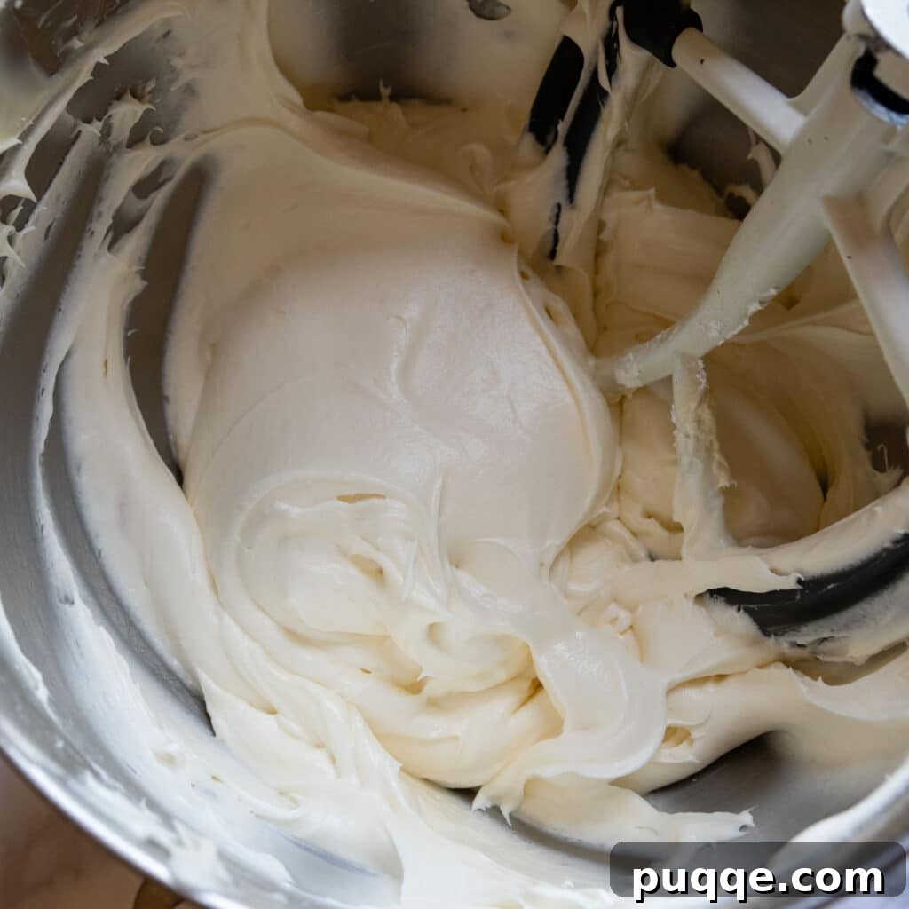 Tropical & Tender Gluten-Free Hummingbird Cake 7 Smooth and fluffy cream cheese frosting in a mixing bowl, showing its light texture.