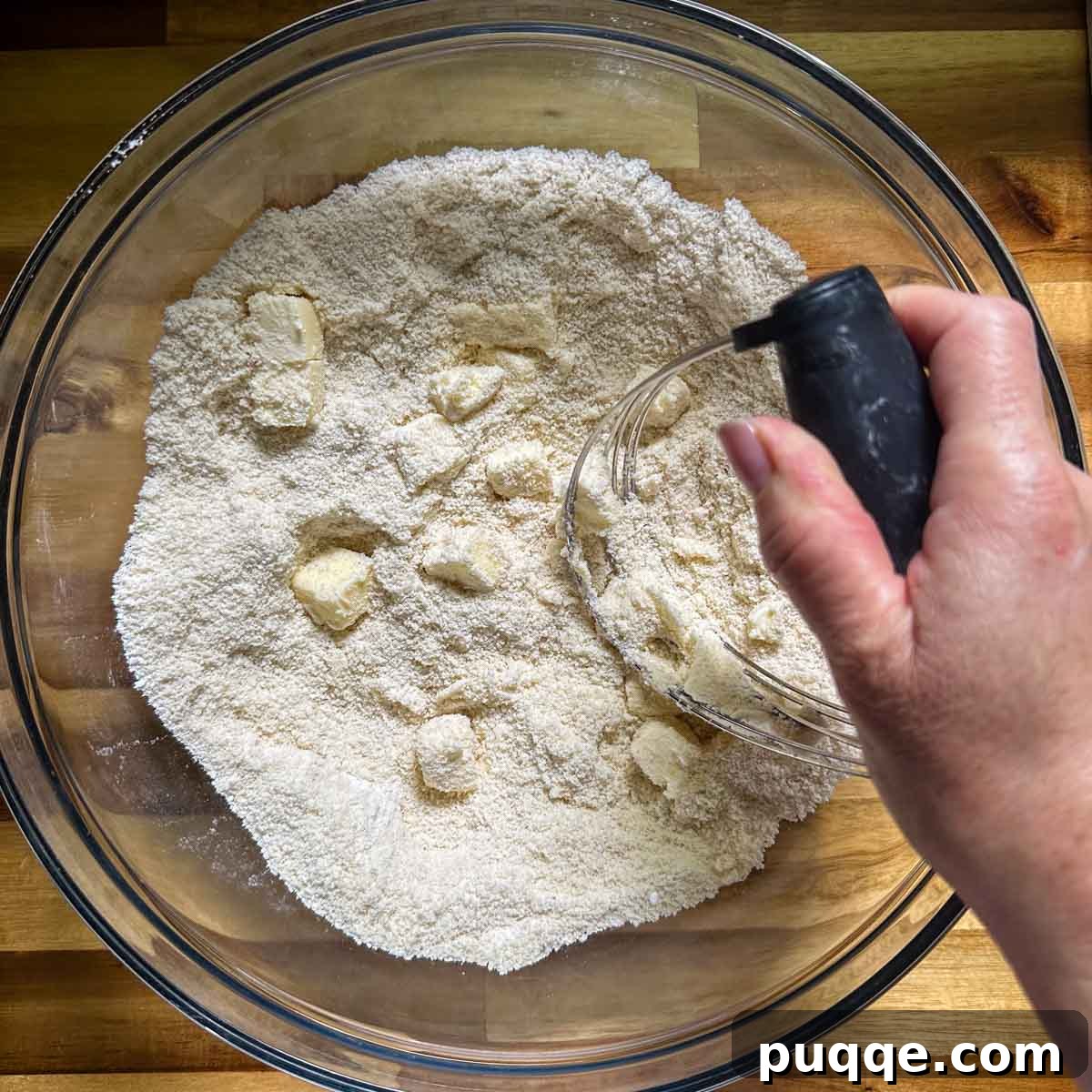 Cold butter being worked into the dry ingredients with a pastry blender.