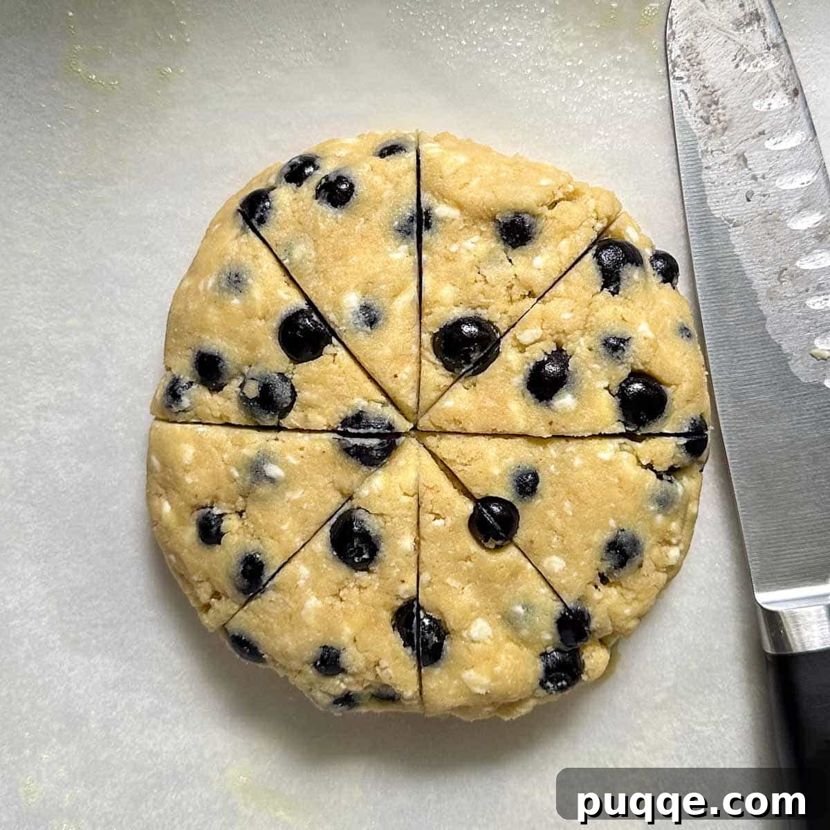 The scone dough shaped into a disk and sliced into 8 wedges on a baking sheet.