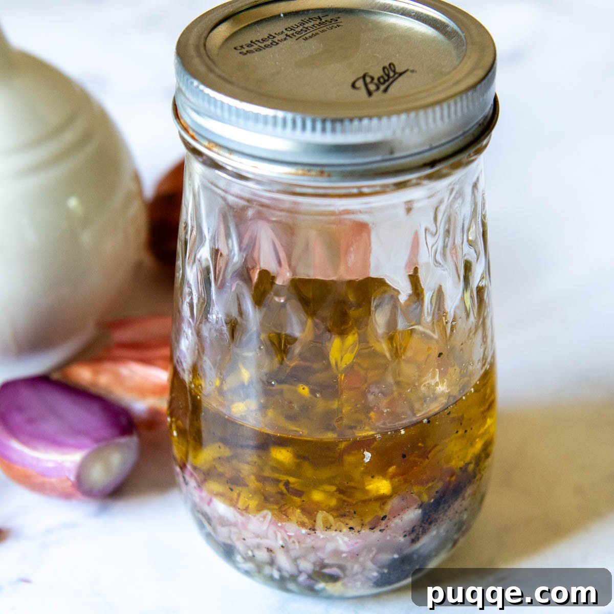 A glass jar filled with the vibrant homemade vinaigrette dressing ingredients, ready to be shaken and combined.