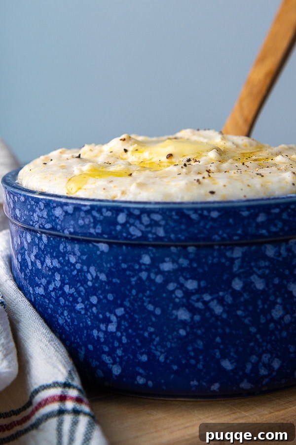 A wooden spoon rests in a bowl of perfectly cooked, creamy grits, highlighting its inviting texture.