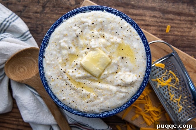 An overhead shot of a bowl of creamy grits in a blue bowl, topped with a pat of melting butter, highlighting its inviting texture.