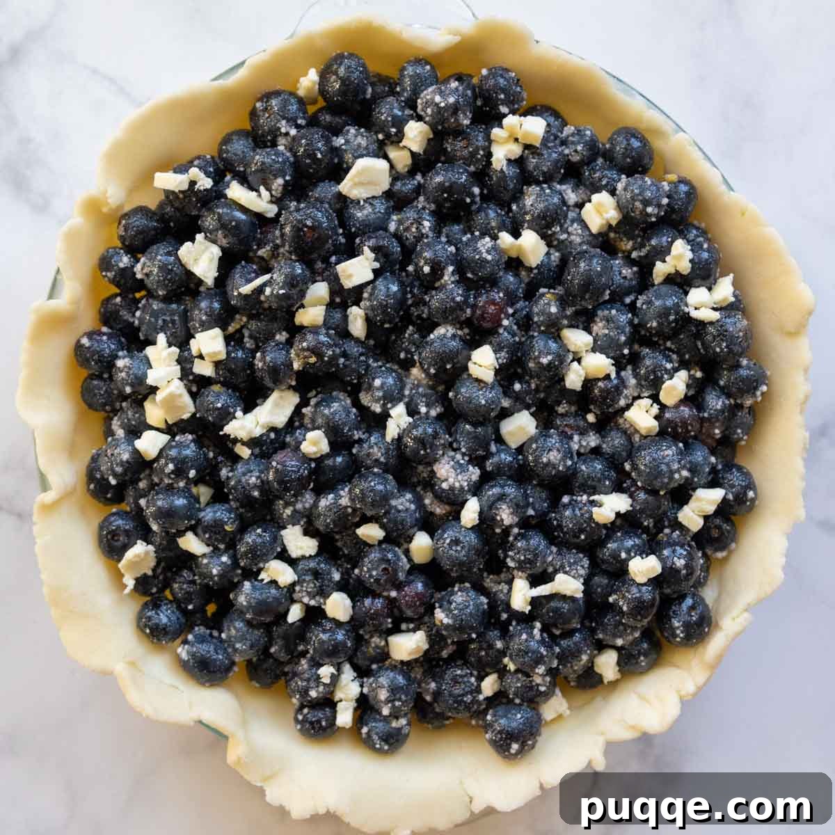 A top-down view of the vibrant blueberry filling nestled in the pie crust, awaiting its lattice topping.