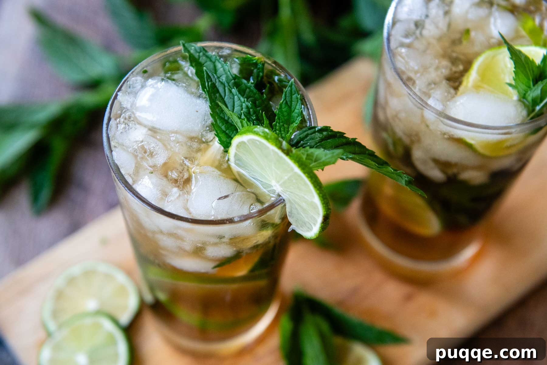A top-down view of two beautifully garnished dark rum mojitos resting on a rustic wooden board, showcasing their vibrant colors and inviting presentation.