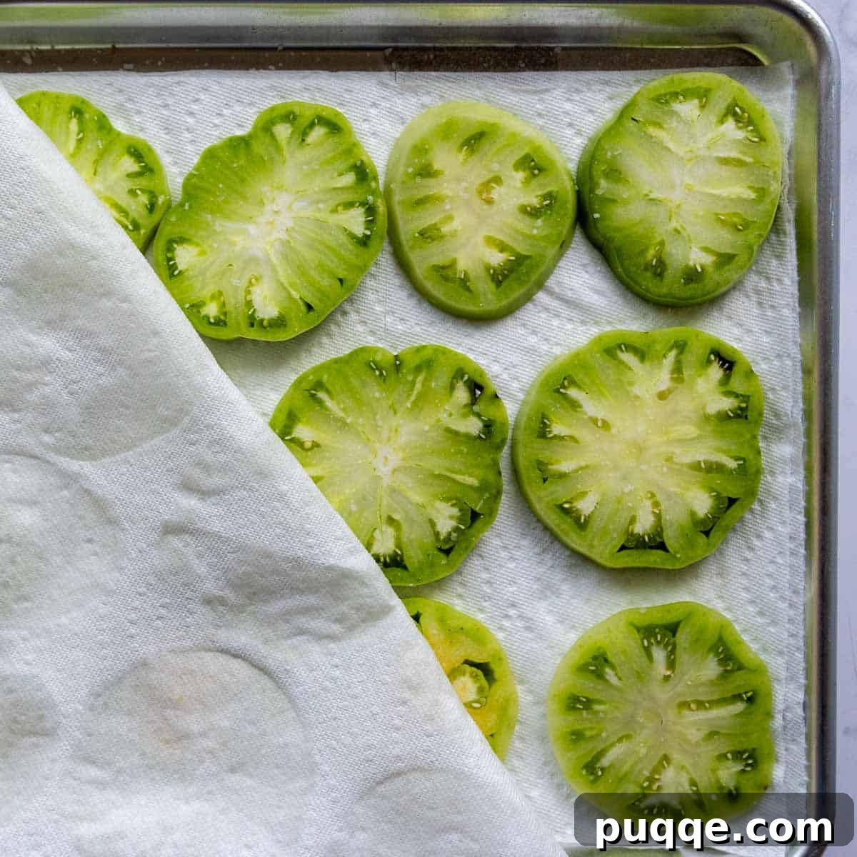 Green tomatoes lined on paper towels, lightly salted to draw out moisture.