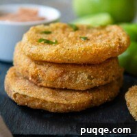 A stack of GF fried green tomatoes on a black tray.