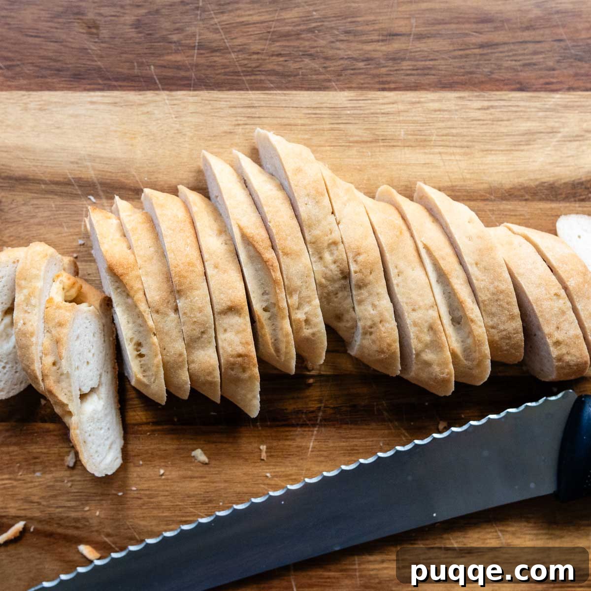 a baguette sliced on a wooden cutting board.