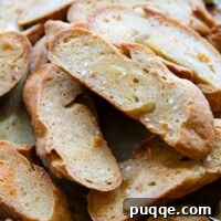 a close up of crostini piled up on each other with garlic in the background.