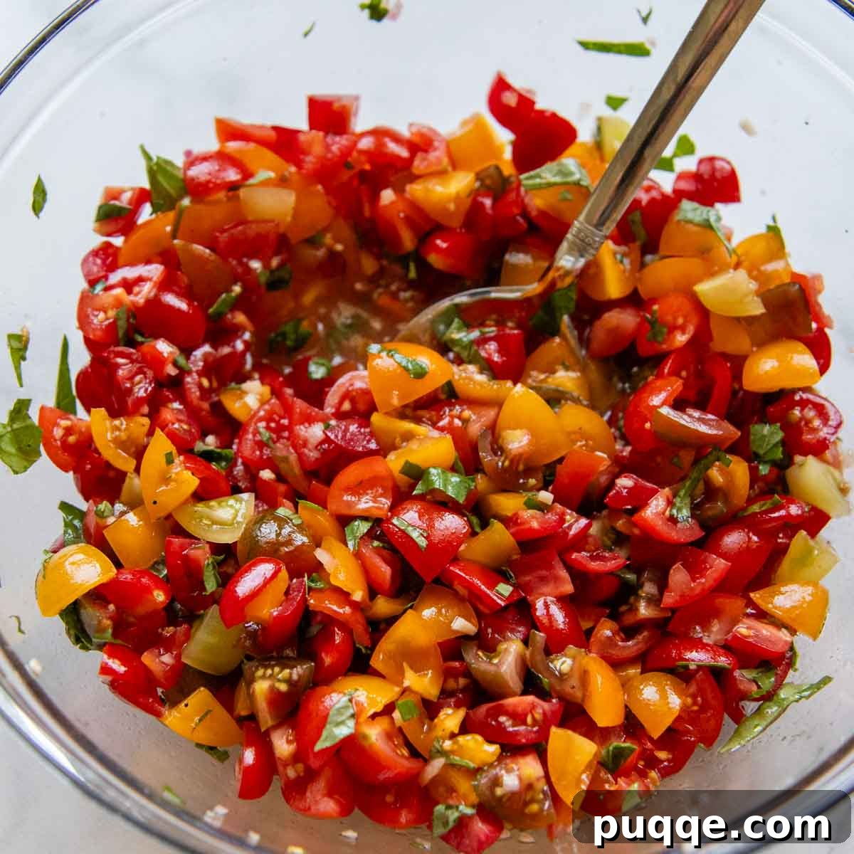 Savory Gluten-Free Italian Bruschetta 5 a large bowl with diced tomatoes and fresh basil being stirred.
