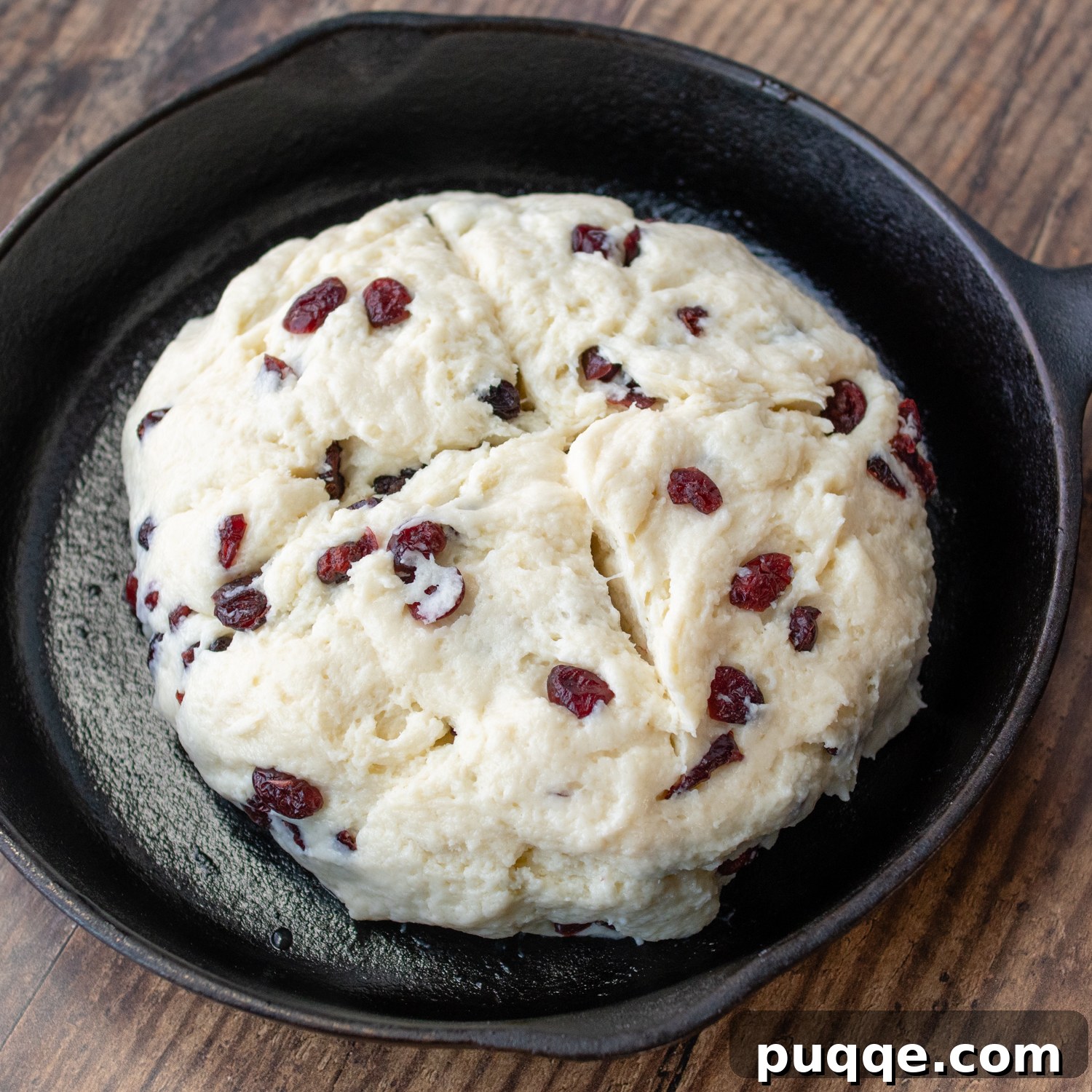 Melt-in-Your-Mouth Sweet Irish Soda Bread 6 A round loaf of Irish soda bread dough in a cast iron pan with a characteristic 'X' scored on top, ready for baking.