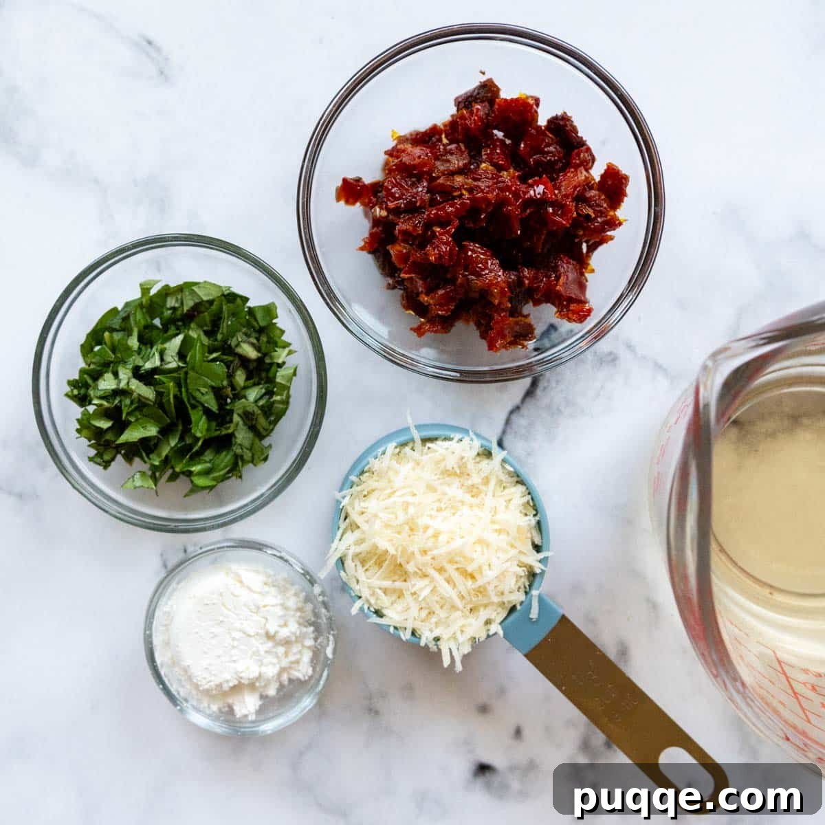 Crave-Worthy Gluten-Free Chicken Meatballs 5 A selection of fresh ingredients neatly prepped for the creamy sun-dried tomato sauce, including minced garlic, chopped basil, grated Parmesan cheese, and sun-dried tomatoes.