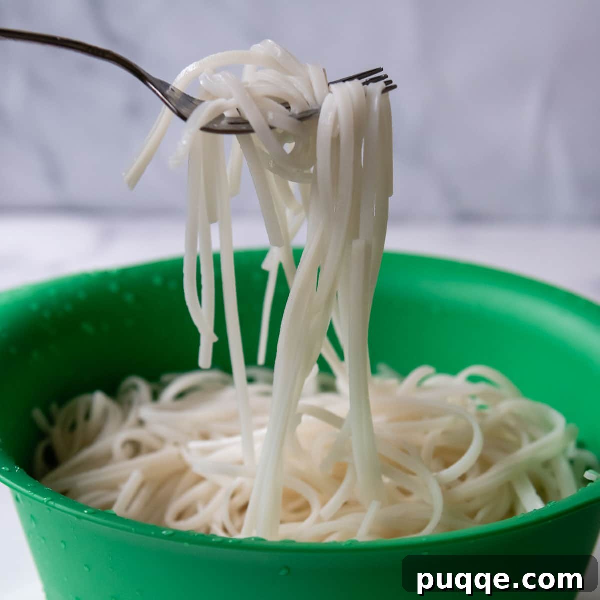 Soaking Rice Noodles rice noodles being lifted out of the bowl with a fork.