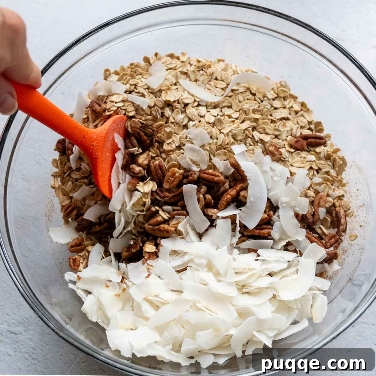 Heavenly Spiced Gluten-Free Muesli Bliss 4 Dry ingredients like gluten-free oats, pecans, and coconut flakes being mixed into the spiced wet ingredients in a large bowl.