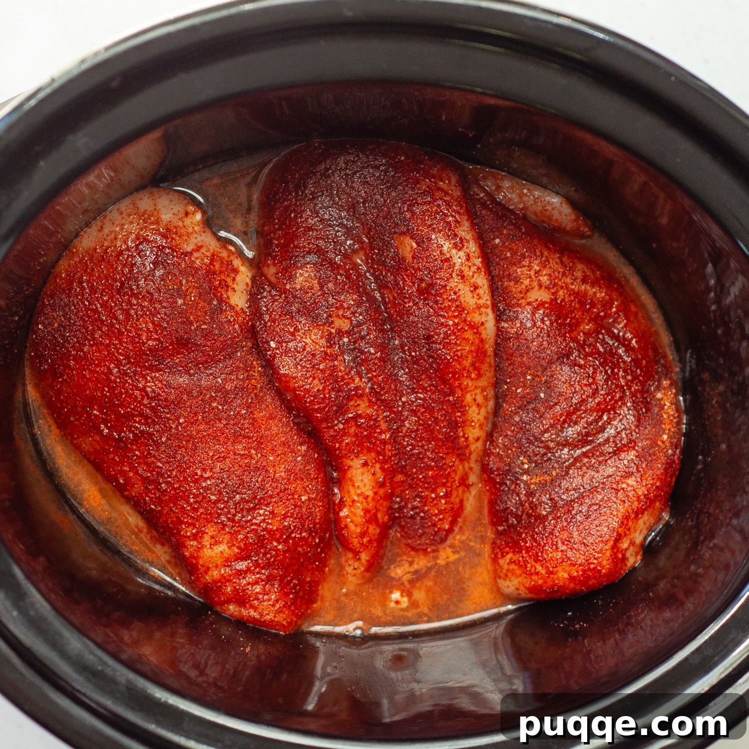 Quick Prep Slow Cooker BBQ Pulled Chicken 3 Seasoned chicken breasts arranged in a slow cooker, ready for cooking.