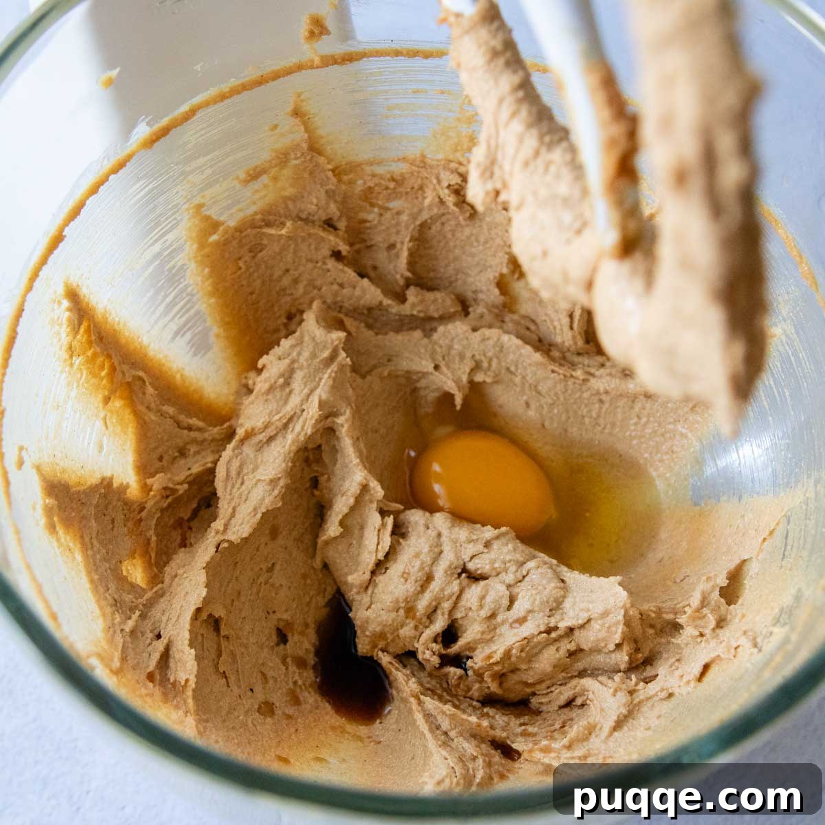 Melt-in-Your-Mouth Peanut Butter Oat Flour Cookies 3 Creamy cookie dough in a glass bowl with an egg carefully placed in the center, ready to be mixed.