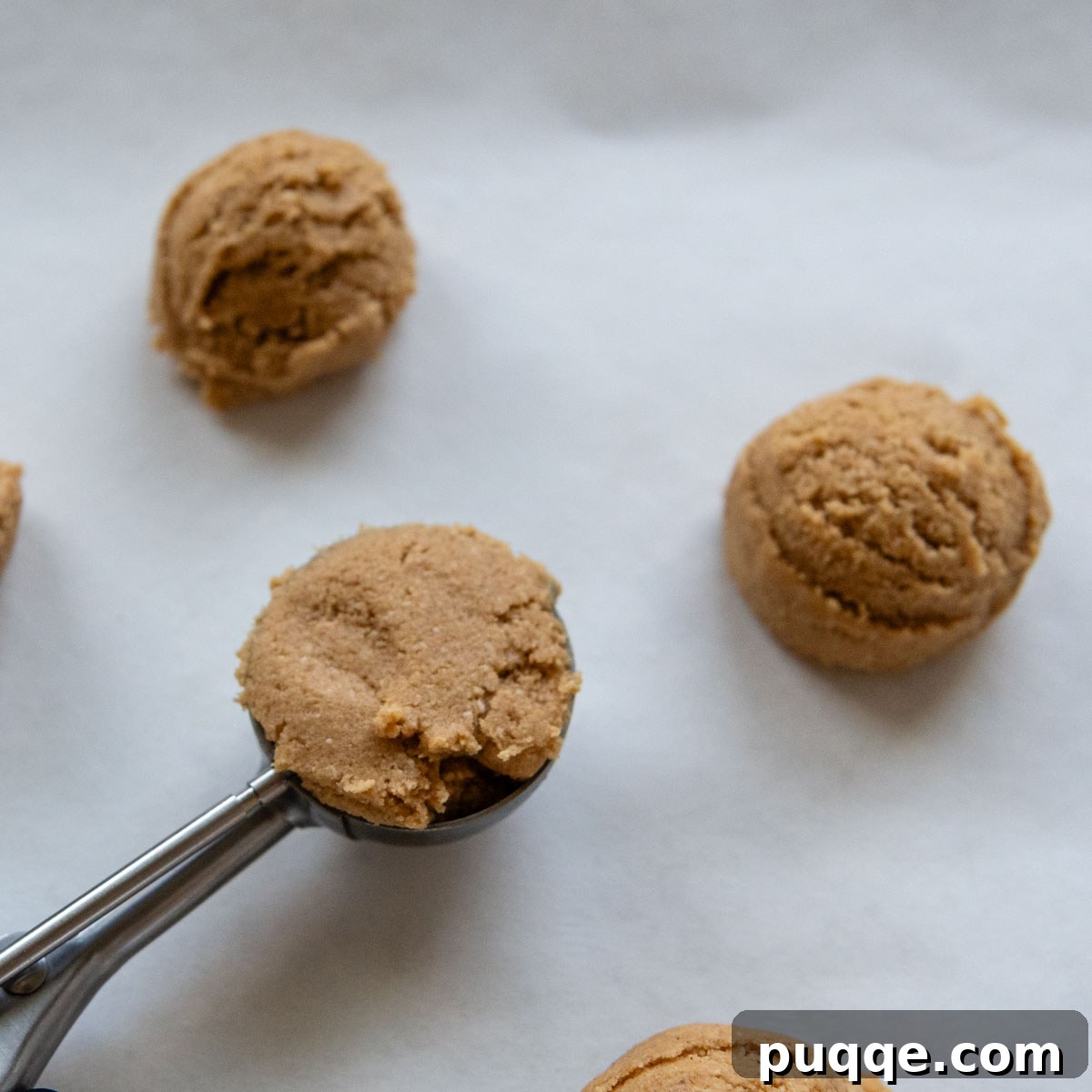 Melt-in-Your-Mouth Peanut Butter Oat Flour Cookies 5 Portioned cookie dough balls, scooped with a medium cookie scoop, arranged neatly on a baking sheet lined with parchment paper.