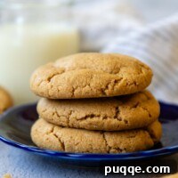 Stack of three peanut butter cookies on a blue plate, highlighting their delightful texture.
