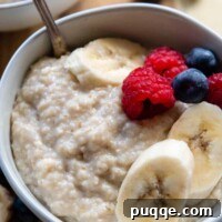 A bowl of creamy oat bran porridge garnished with fresh berries and sliced fruit.