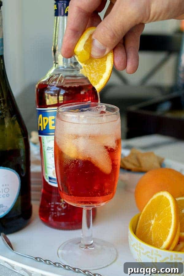 The Definitive Aperol Spritz Recipe 3 A fresh orange slice being squeezed into an Aperol Spritz, illustrating the citrus burst.