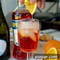 A fresh orange slice being squeezed into an Aperol Spritz, ready to be enjoyed.