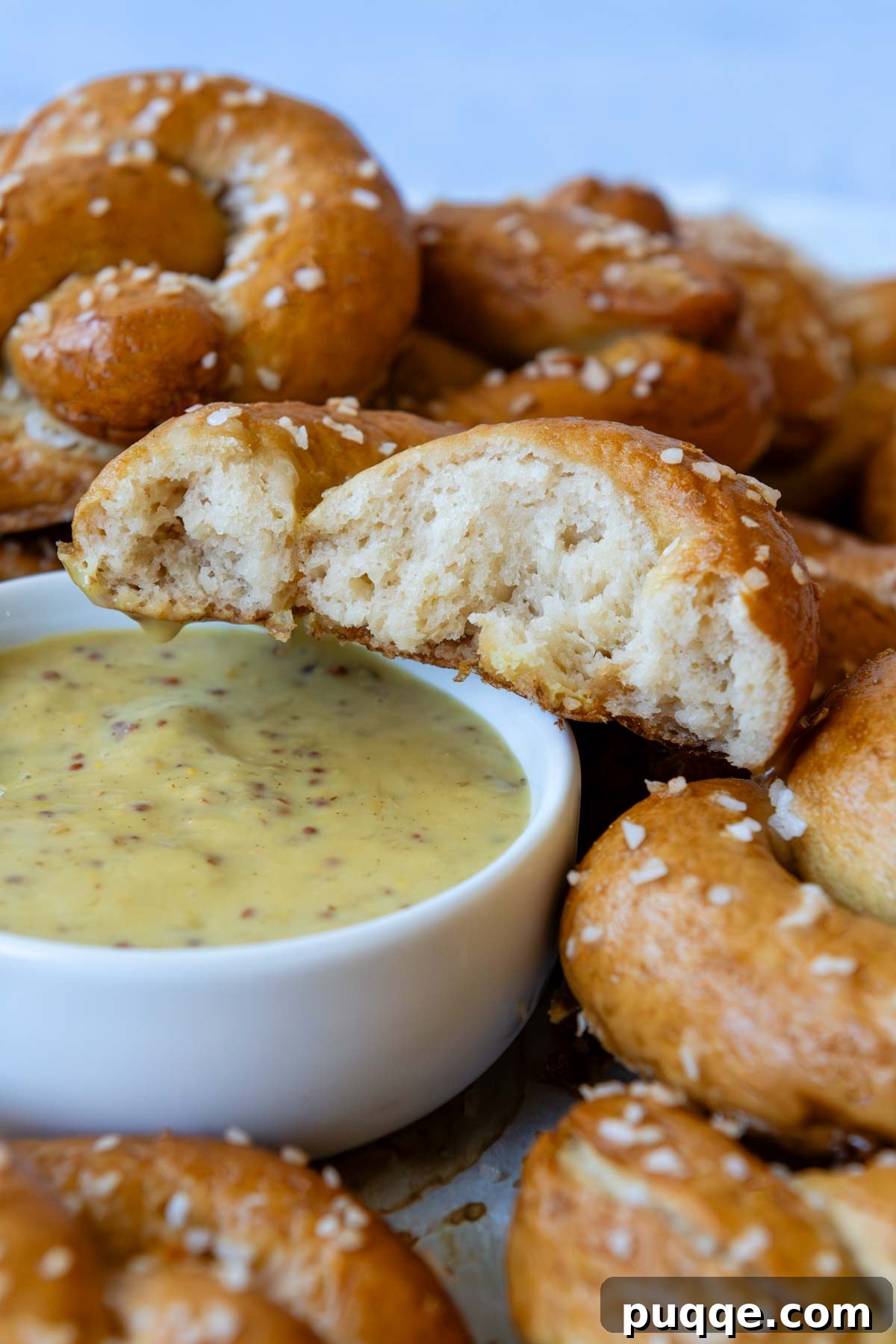 Pillowy Soft Gluten-Free Pretzels Simple Recipe 15 A perfectly baked gluten-free pretzel, sliced open to reveal its soft, airy interior, positioned next to a bowl of mustard dipping sauce.